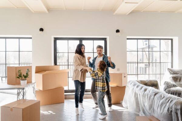 Family joyfully celebrating their new home among moving boxes and furniture.