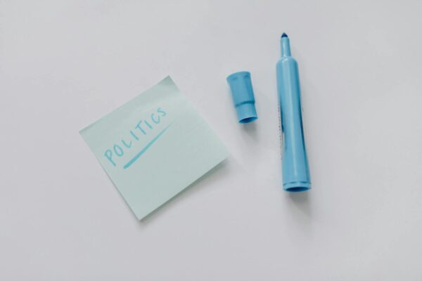 A blue marker and a note reading 'politics' on a white surface, top view.