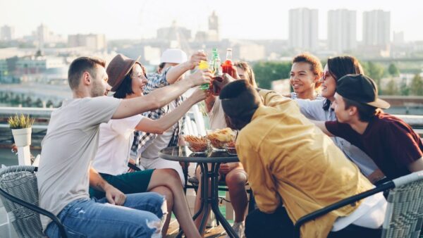 Friends toasting drinks on a rooftop party.