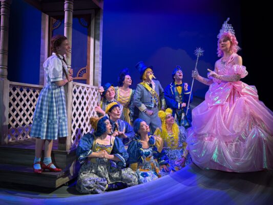 Gillian Weatherford (right) plays Glinda, with Sophie Kaegi as Dorothy and the Munchkins.